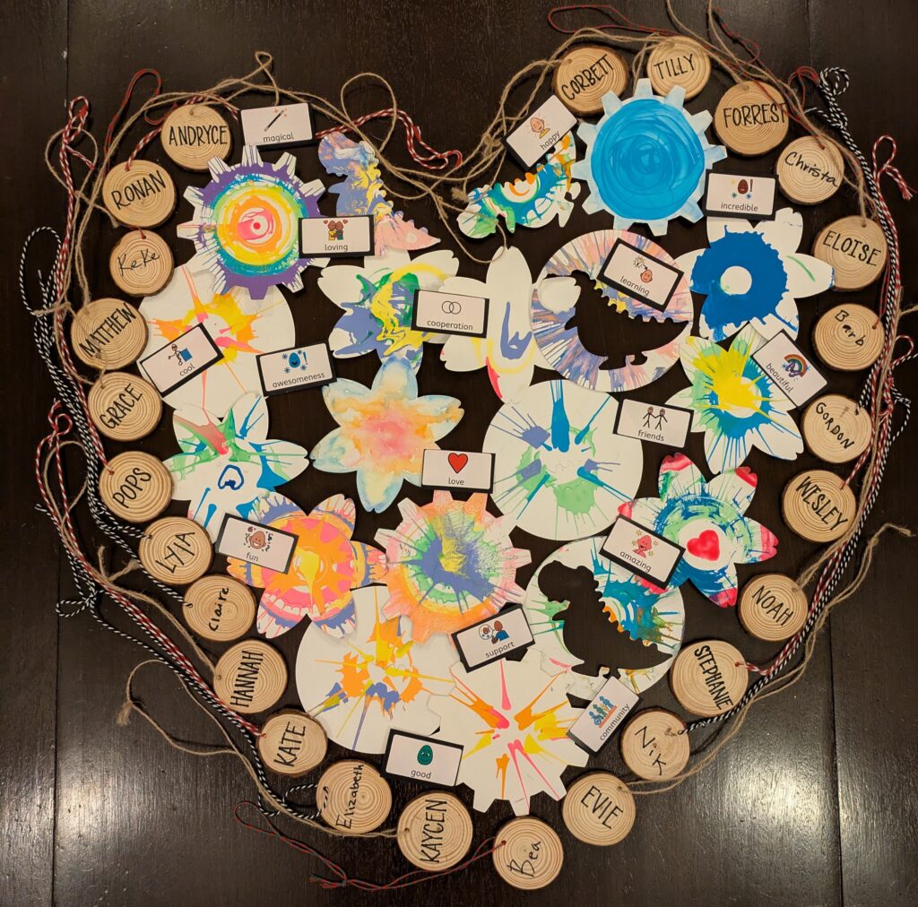 PXL_20250518_035211819 (1) Painted spin art and picture communication symbols of words inside wood cookie name tags in the shape of a heart.