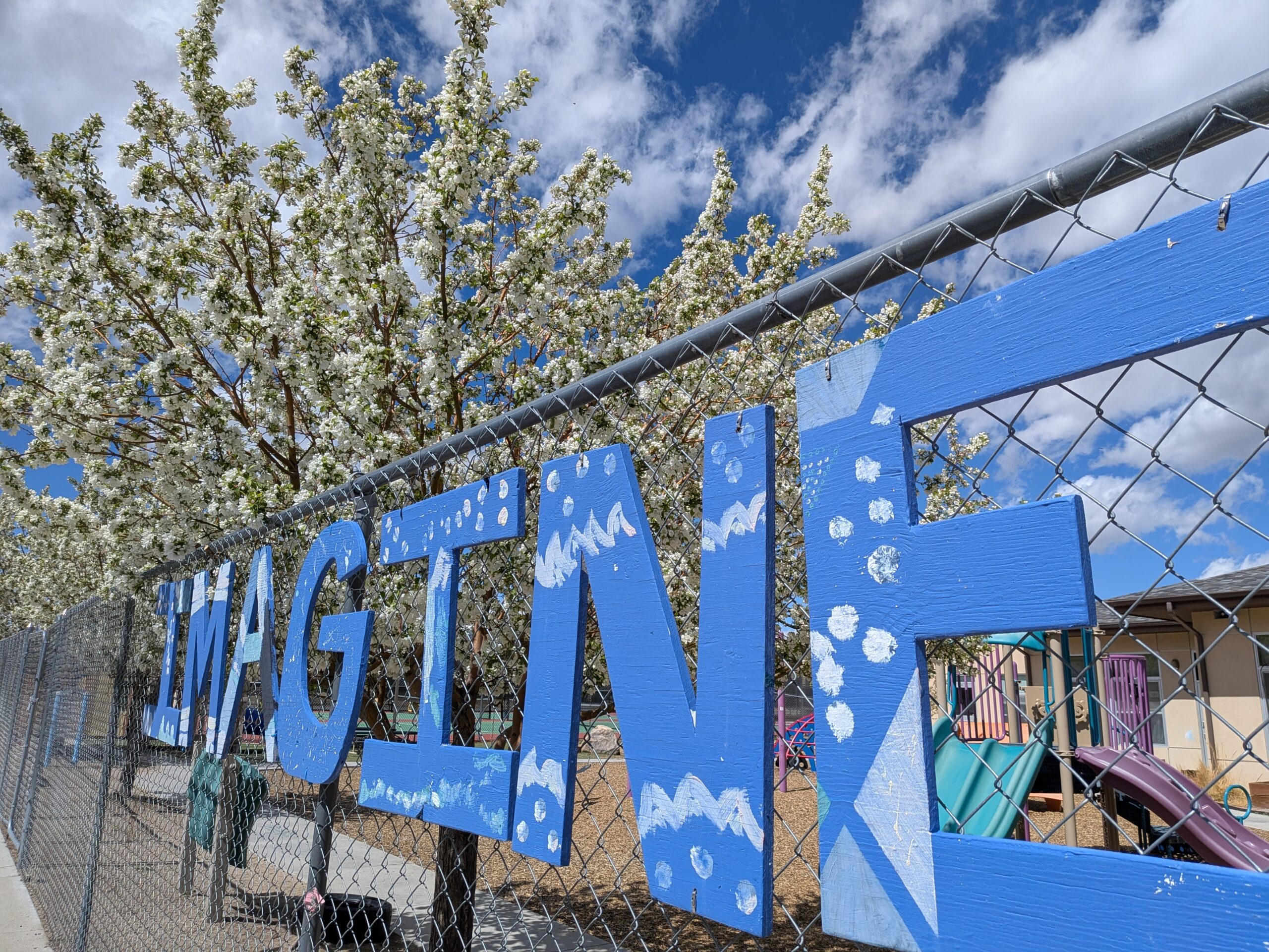 The word imagine painted blue on a fence